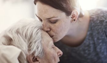 Woman kissing older woman's forehead