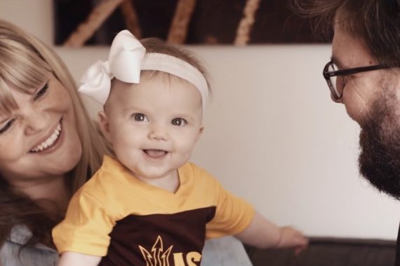 Happy family with small child wearing ASU colors