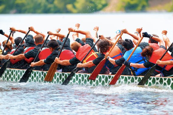 Row team rowing in unison with water life vests on