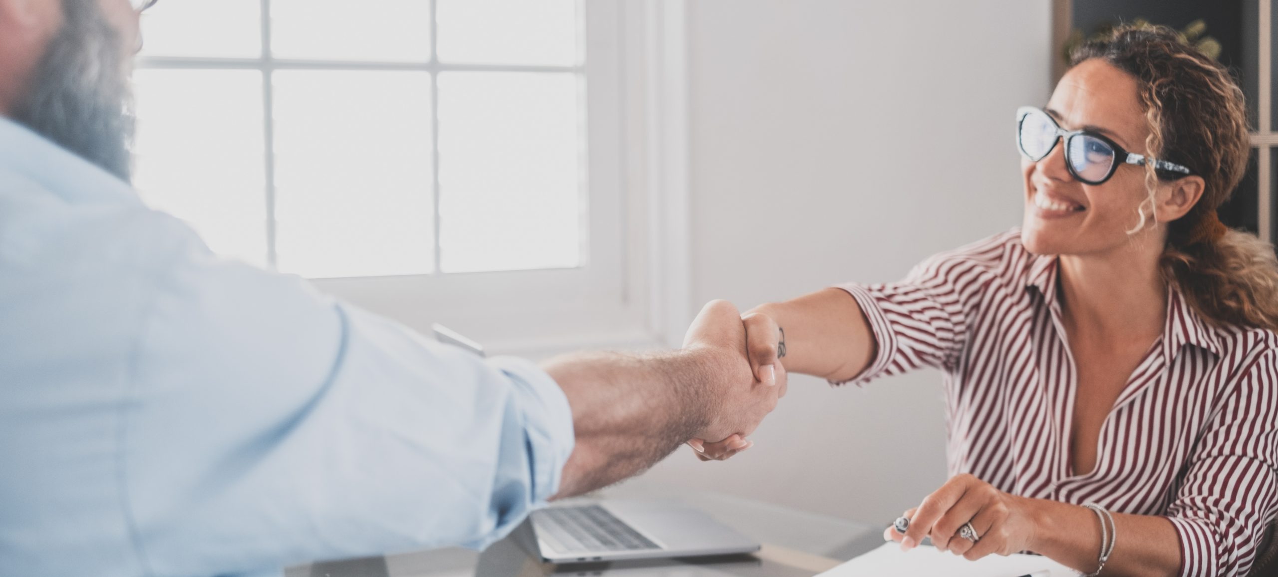 Smiling caucasian female hr manager handshake hire male candidate at job interview make good first impression, happy mixed race client shake hand of bank broker, respect, business agreement concept